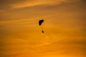 het silhouet van de paramotor bij zonsondergang foto