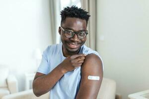 covid-19 vaccinatie. portret van gelukkig gevaccineerd Afrikaanse Mens tonen zijn arm na coronavirus antiviraal vaccin schot . covid immunisatie campagne concept. foto