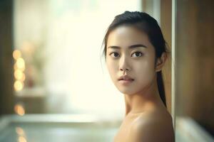 aantrekkelijk versheid Aziatisch vrouw schoon gezicht vers water met zorg kijken naar spiegel in badkamer huis concept door ai gegenereerd foto