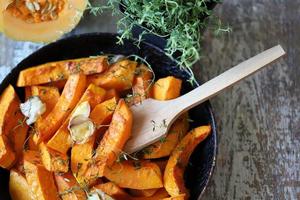 gebakken pompoenschijfjes in een pan met kruiden en knoflook foto