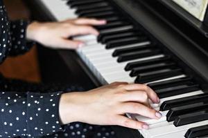handen van een jonge meisjespianist op de toetsen van een synthesizer