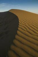 een woestijn met zand duinen en een blauw lucht foto