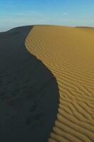 een woestijn met zand duinen en blauw lucht foto