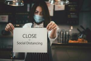 serveerster Holding een teken dichtbij sociaal afstand nemen in een coffeeshop foto