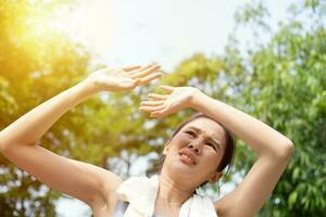 sport Aziatisch vrouw krijgt moe en krijgen duizelig, voelen slecht pijn en lijden van warmte beroerte buitenshuis wanneer jogging of oefening buitenshuis met sterk zonlicht in zomer seizoen. zonnesteek en warmte Golf concept. foto