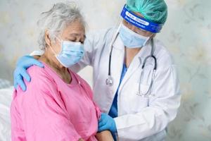 arts die aziatische senior of oudere oude damevrouwenpatiënt controleert die een gezichtsmasker in het ziekenhuis dragen om infectie covid-19 coronavirus te beschermen. foto