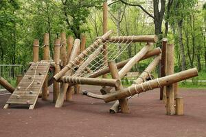 houten speelplaats gemaakt van natuurlijk milieuvriendelijk materiaal in openbaar stad park. modern veiligheid kinderen buitenshuis apparatuur. concept van duurzame levensstijl en ecologie. kinderen rust uit en spellen Aan Open lucht foto