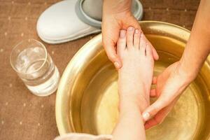 het wassen vrouw voet in een speciaal houder door mannetje masseur in spa salon. foto