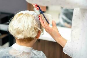 vrouw kapper styling kort wit haar- van de jong blond vrouw met handen en kam in een haar- salon. foto