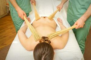 jong vrouw hebben dubbele samurai massage met bamboe bezems in spa. ontspanning massage concept. foto