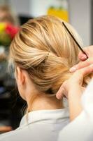 detailopname kapper styling blond haar- Aan de terug van de hoofd in een schoonheid salon. foto