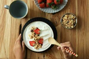 aan het eten Grieks yoghurt en muesli voor ontbijt foto