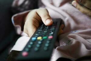 close-up van vrouwen hand met tv-afstandsbediening. foto