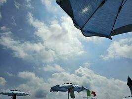 structuur van paraplu's Bij de strand met de wolken en de zee in de zomer seizoen 2023 in spotorno, Italië foto