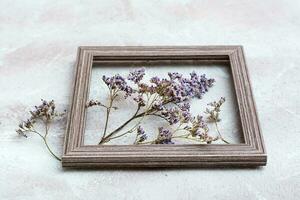 droog Purper bloemen in een houten kader Aan een getextureerde achtergrond. romantisch groet wijnoogst kaart foto