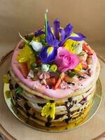 schot van melkmeisje taart gemaakt van wit room met chocola glazuur, versierd met bloemen en bessen foto