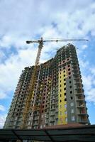 bouw van een hoogbouw gebouw door toren kranen tegen een blauw lucht met wolken foto