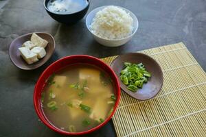 miso soep of Japans miso soep in kom Aan de tafel. Japans keuken in de het formulier van soep met dashi ingrediënten, tofu, zeevruchten, groenten, en bekroond met miso naar smaak foto