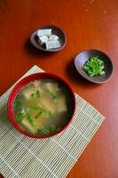 miso soep of Japans miso soep in kom Aan de tafel. Japans keuken in de het formulier van soep met dashi ingrediënten, tofu, zeevruchten, groenten, en bekroond met miso naar smaak foto