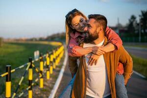 gelukkig glimlachen paar genieten van zonsondergang. Mens is draag- Aan terug zijn vrouw. foto