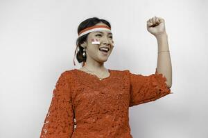 een jong Aziatisch vrouw met een gelukkig geslaagd uitdrukking vervelend rood kebaya en hoofdband geïsoleerd door wit achtergrond. Indonesië's onafhankelijkheid dag concept. foto