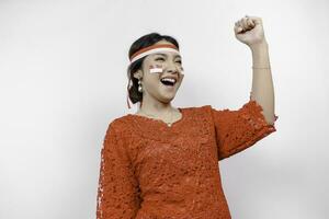 een jong Aziatisch vrouw met een gelukkig geslaagd uitdrukking vervelend rood kebaya en hoofdband geïsoleerd door wit achtergrond. Indonesië's onafhankelijkheid dag concept. foto