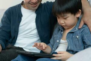 gelukkig single vader spelen onderwijzen gebruik makend van tablet met de weinig jongen. familie is gelukkig en opgewonden in de huis. vader en zoon hebben uitgeven tijd samen, mooi zo papa , verslaving repareren, handvat, controle foto