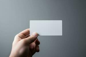 hand- Holding een blanco bedrijf kaart Aan een grijs achtergrond, dichtbij omhoog mockup foto