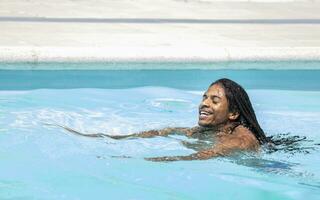 zwart Afro-Amerikaans met dreadlocks zwemmen in een zwembad. foto