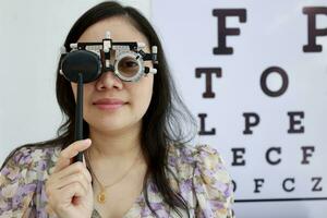 vrouw vervelend beproeving kader van oog testen. oog tentamen concept, vrouw oog test in kliniek, Dames oog tentamen in kliniek foto