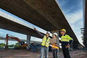 team van 3 Aziatisch ingenieurs inspecteren snelweg bouw. Aziatisch architect en volwassen leidinggevende vergadering Bij snelweg bouw plaats foto