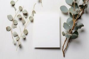 blanco groet papier kaart, uitnodiging mockup tafereel top visie met eucalyptus boom takken. elegant schrijfbehoeften Aan wit tafel achtergrond. ai gegenereerd foto