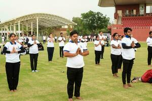 nieuw Delhi, Indië, juni 21, 2023 - groep yoga oefening sessie voor mensen Bij Yamuna sport- complex in Delhi Aan Internationale yoga dag, groot groep van volwassenen Bijwonen yoga klasse in krekel stadion foto