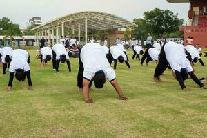 nieuw Delhi, Indië, juni 21, 2023 - groep yoga oefening sessie voor mensen Bij Yamuna sport- complex in Delhi Aan Internationale yoga dag, groot groep van volwassenen Bijwonen yoga klasse in krekel stadion foto