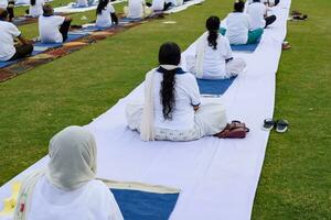 nieuw Delhi, Indië, juni 21, 2023 - groep yoga oefening sessie voor mensen Bij Yamuna sport- complex in Delhi Aan Internationale yoga dag, groot groep van volwassenen Bijwonen yoga klasse in krekel stadion foto