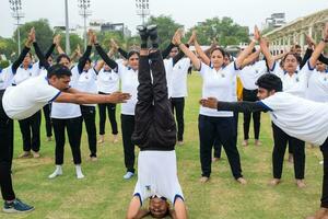 nieuw Delhi, Indië, juni 21, 2023 - groep yoga oefening sessie voor mensen Bij Yamuna sport- complex in Delhi Aan Internationale yoga dag, groot groep van volwassenen Bijwonen yoga klasse in krekel stadion foto