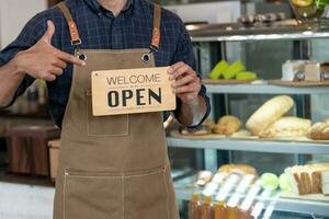 bedrijf Mens eigenaar tonen teken Open Aan de eerste dag van bedrijf. garanties veiligheid, netheid, Open de koffie winkel. Open voor nieuw normaal. klein bedrijf, welkom, restaurant, huis gemaakt foto