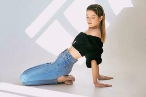 mooi slank jong kaukasisch vrouw in zwart bloeien en jeans Aan wit achtergrond in foto studio