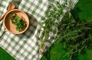 wit houten tafel gedekt met groen tafelkleed en Koken gebruiksvoorwerpen. visie van top. leeg tafelkleed voor Product montage. vrij ruimte voor uw tekst. gemaakt met generatief ai technologie. foto