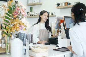 Azië barista ober nemen bestellen van klant in koffie winkel, cafe eigenaar schrijven drinken bestellen Bij teller bar. foto