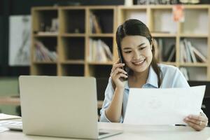 glimlachen zakenvrouw pratend Aan smartphone terwijl aan het wachten cliënt in kantoor foto