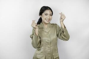 een jong Aziatisch vrouw in bruin khaki uniform tonen inschrijving gevoel door vormgeven hart met haar vingers. Indonesisch regering arbeider. foto