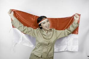 glimlachen regering arbeider vrouw Holding Indonesië's vlag geïsoleerd door wit achtergrond. pns vervelend khaki uniform. Indonesië's onafhankelijkheid dag concept. foto