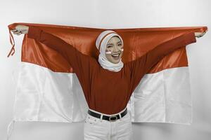 gelukkig glimlachen Indonesisch moslim vrouw vervelend rood top en wit hijab Holding Indonesië's vlag naar vieren Indonesië onafhankelijkheid dag. geïsoleerd door wit achtergrond. foto
