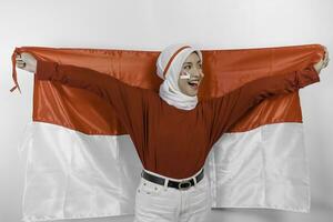 gelukkig glimlachen Indonesisch moslim vrouw vervelend rood top en wit hijab Holding Indonesië's vlag naar vieren Indonesië onafhankelijkheid dag. geïsoleerd door wit achtergrond. foto