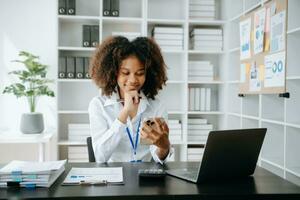 vrouw die smartphone gebruikt voor mobiele betalingen online winkelen, omni-channel, zittend op tafel, virtuele pictogrammen grafische interface-scherm in ochtendlicht foto