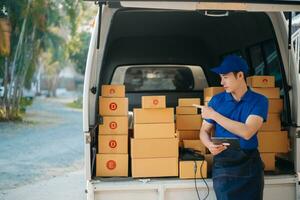 glimlachen levering Mens staand in voorkant van zijn busje met Holding doos en tablet levering huis en Verzending foto