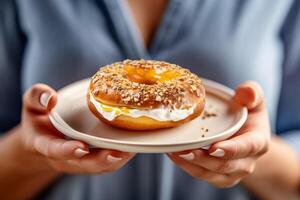 vrouw Holding bord met creme brulee bagel gevuld met room kaas en gouden korst Aan top. detailopname van handen, voedsel. ai generatief foto