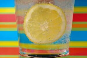 limonade koolzuurhoudend drinken in een Doorzichtig glas met kleurrijk achtergrond tonen koolzuurhoudend bubbels foto