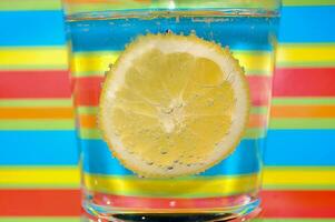 limonade koolzuurhoudend drinken in een Doorzichtig glas met kleurrijk achtergrond tonen koolzuurhoudend bubbels foto